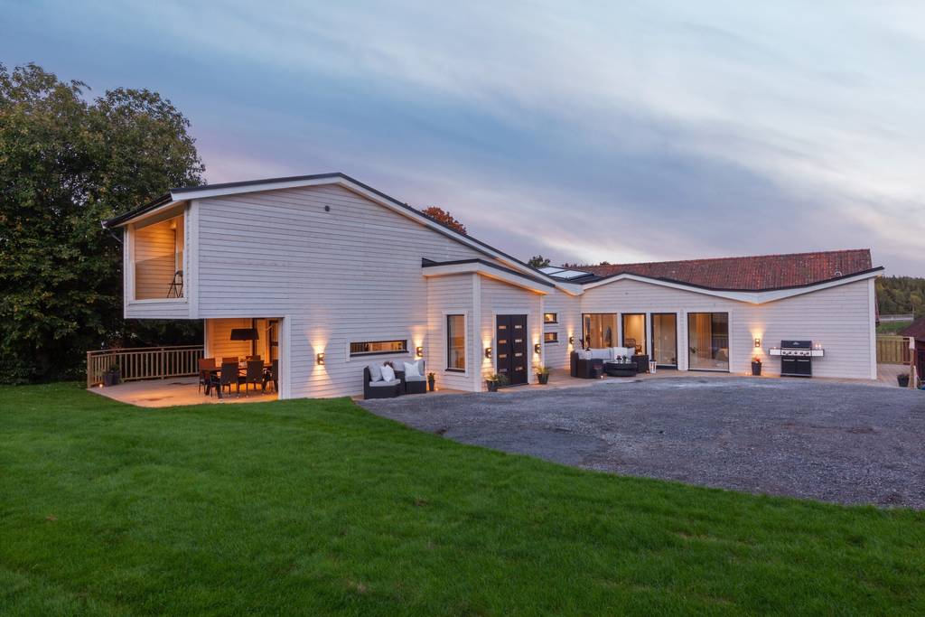“Modern villa med uppfart och kvällsbelysning.