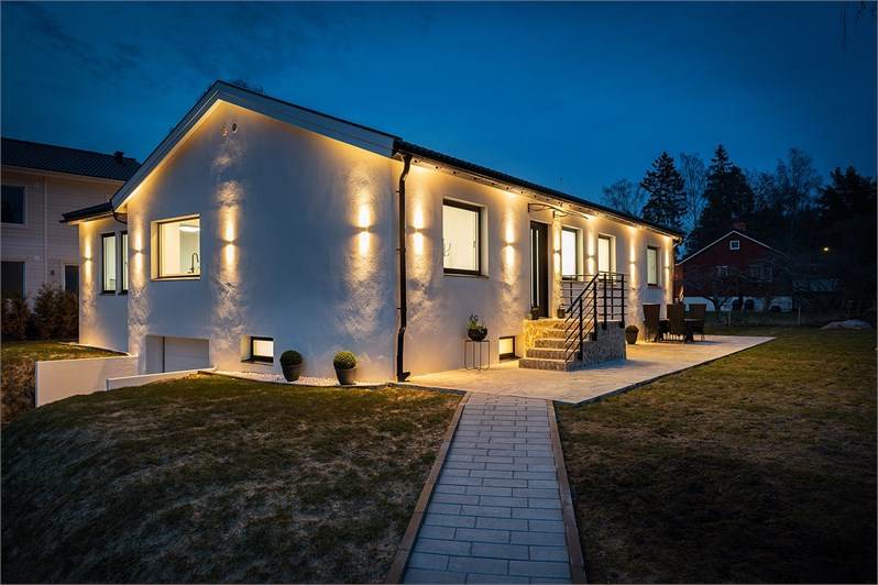 Hus med upplyst entré och stensatt gång.