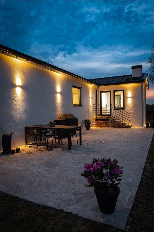 Villa med stensatt uteplats och kvällsbelysning.